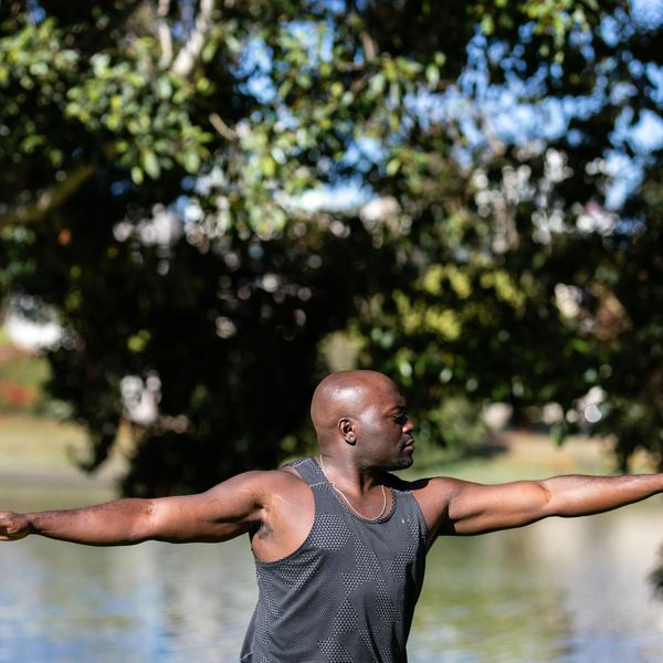 Person stretching outdoors, radiating energy and vitality against a natural backdrop.
